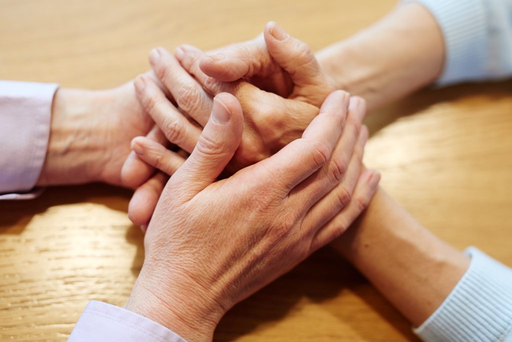 Two people clasping hands in comfort